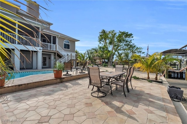 view of patio / terrace with outdoor dining area, stairway, fence, and an outdoor pool