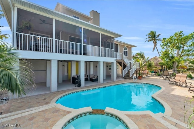 view of pool with ceiling fan, a pool with connected hot tub, a sunroom, stairs, and a patio area