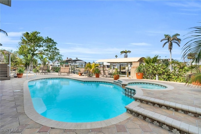 view of pool with a patio area, a pool with connected hot tub, and fence