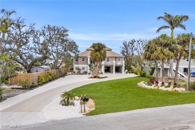 view of front of property featuring fence, a residential view, driveway, a front lawn, and stairs