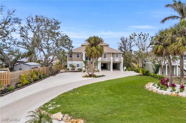 back of property with driveway, fence, stairway, and a yard