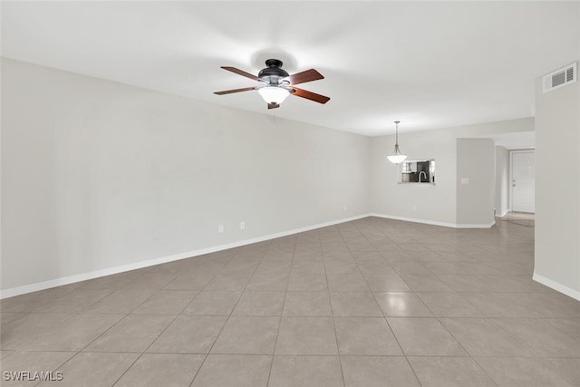 spare room with ceiling fan, light tile patterned floors, visible vents, and baseboards