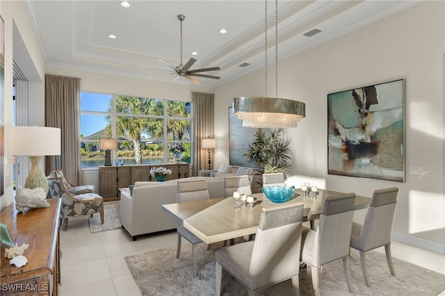 dining room with light tile patterned floors, a tray ceiling, ornamental molding, and ceiling fan