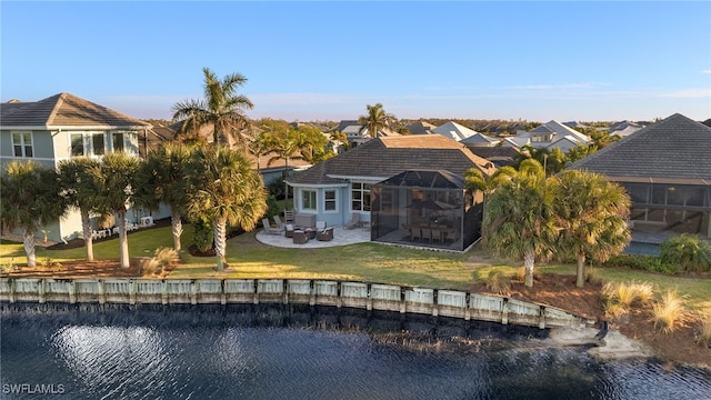 back of house with a patio, a water view, glass enclosure, and a lawn