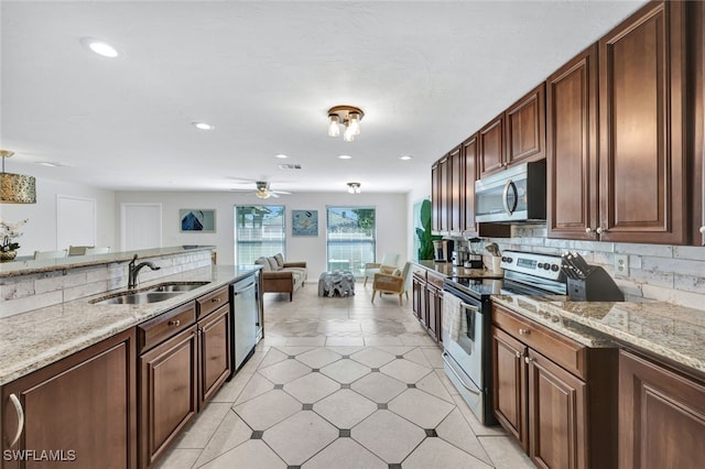 kitchen featuring light stone countertops, sink, ceiling fan, stainless steel appliances, and tasteful backsplash