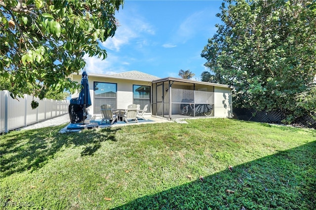 rear view of house featuring a patio, a sunroom, and a lawn