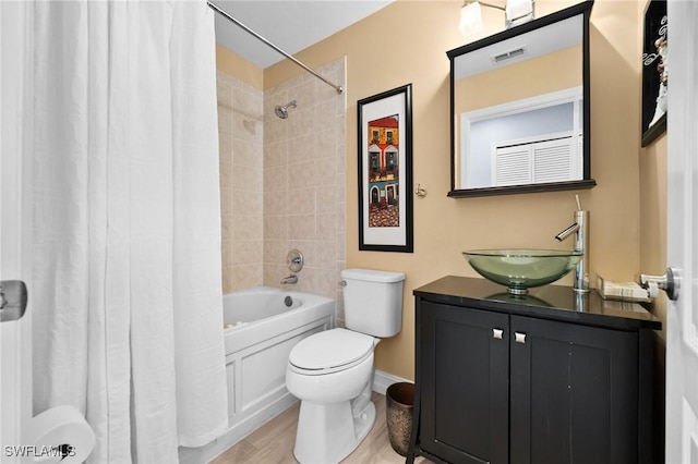 bathroom featuring visible vents, toilet, shower / tub combo with curtain, wood finished floors, and vanity