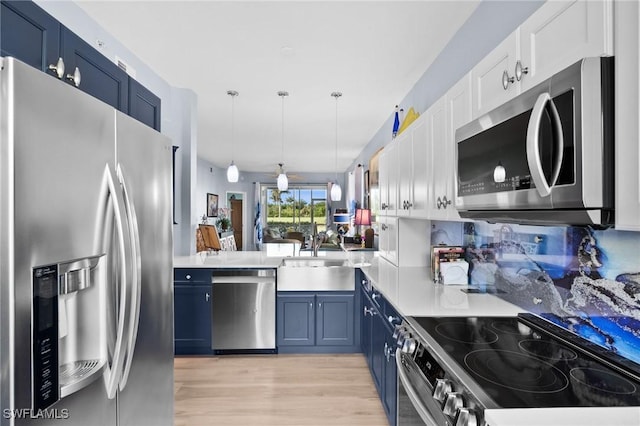 kitchen with a sink, appliances with stainless steel finishes, blue cabinetry, and light wood-style floors