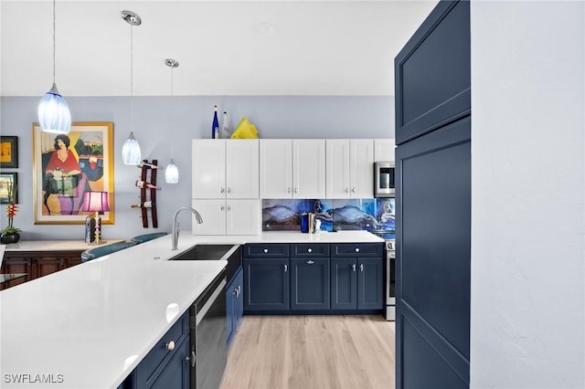 kitchen with tasteful backsplash, white cabinets, stainless steel appliances, light countertops, and a sink