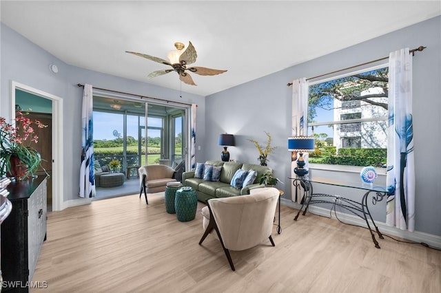 living area featuring ceiling fan, baseboards, and light wood-style floors