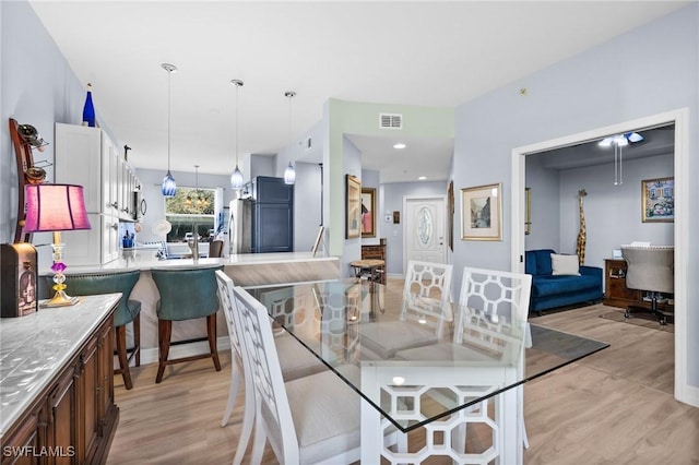 dining space with light wood-style flooring and visible vents