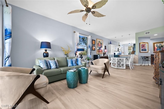 living room featuring a ceiling fan, visible vents, and light wood-style flooring