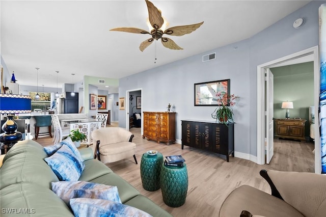 living area featuring light wood finished floors, ceiling fan, visible vents, and baseboards