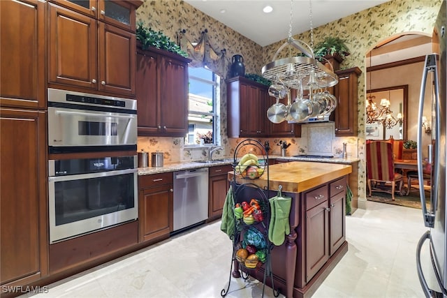 kitchen featuring decorative backsplash, sink, butcher block counters, and stainless steel appliances