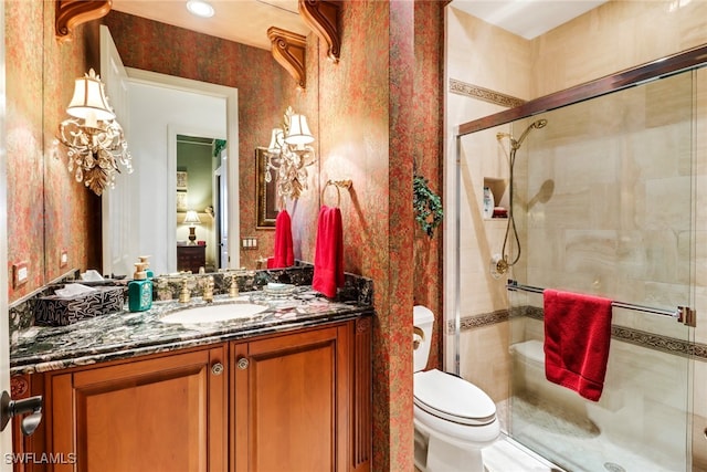 bathroom with vanity, toilet, and a shower with door