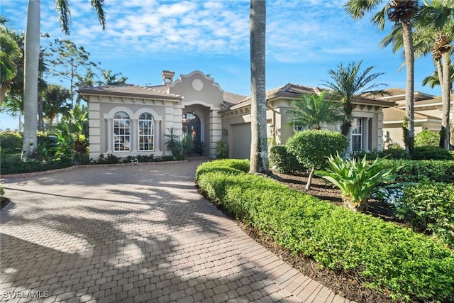 mediterranean / spanish house with decorative driveway, an attached garage, and stucco siding