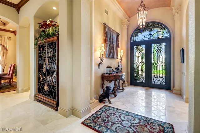 entryway featuring crown molding, french doors, and a chandelier