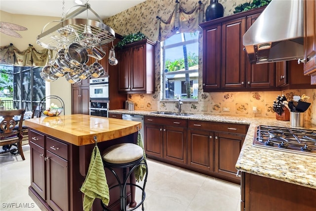 kitchen featuring wood counters, a center island, ventilation hood, sink, and appliances with stainless steel finishes