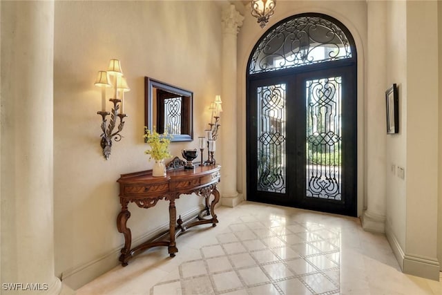 entrance foyer featuring a towering ceiling, baseboards, and french doors