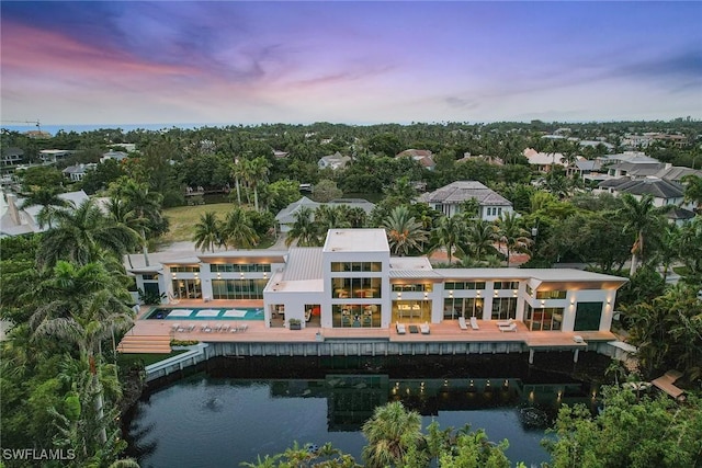 back of property at dusk with a water view