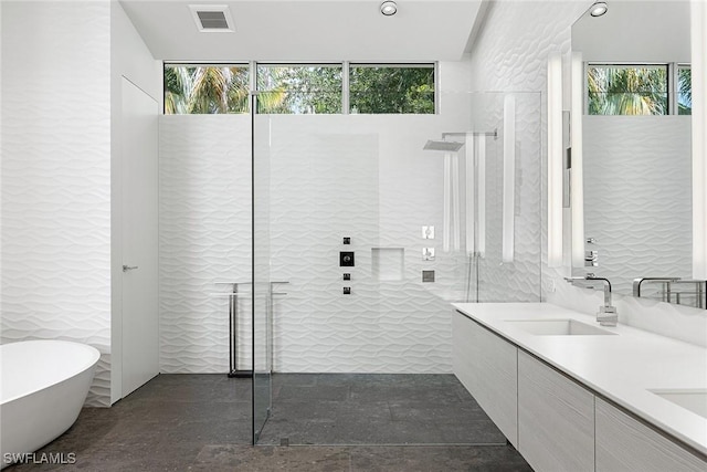 bathroom with a freestanding tub, a walk in shower, a sink, visible vents, and double vanity