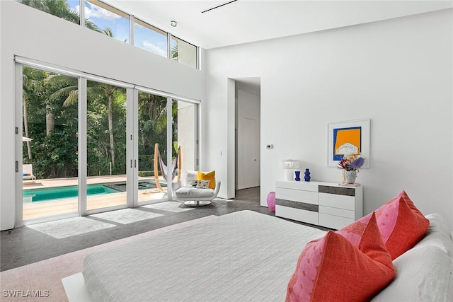 bedroom featuring concrete floors, a towering ceiling, and access to outside