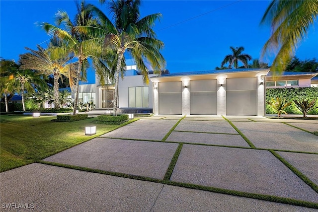 view of front of house with a front yard, concrete driveway, and stucco siding