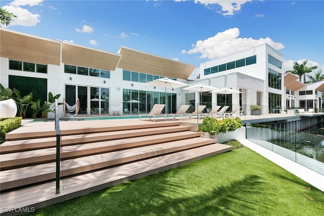 rear view of house featuring an outdoor pool and a yard