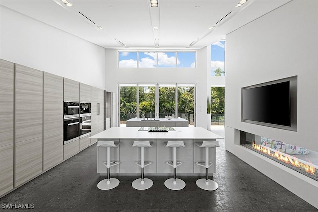 kitchen with a high ceiling, plenty of natural light, modern cabinets, and a breakfast bar area