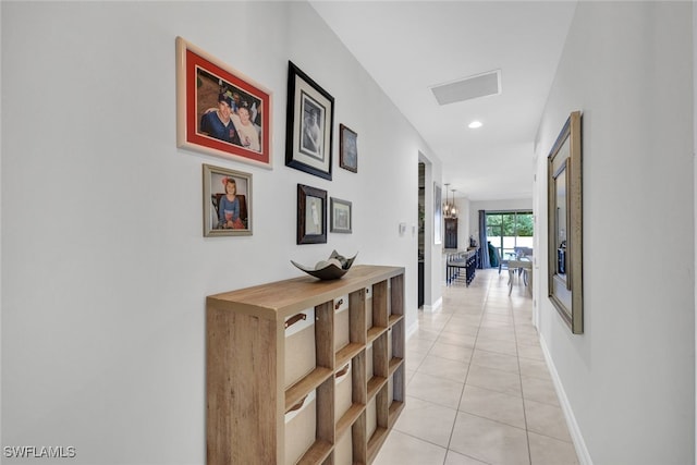 hallway with an inviting chandelier and light tile patterned floors