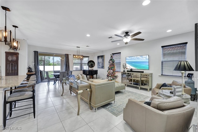 tiled living room featuring ceiling fan with notable chandelier