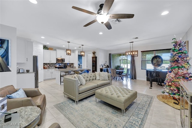 living room with ceiling fan with notable chandelier and light tile patterned floors