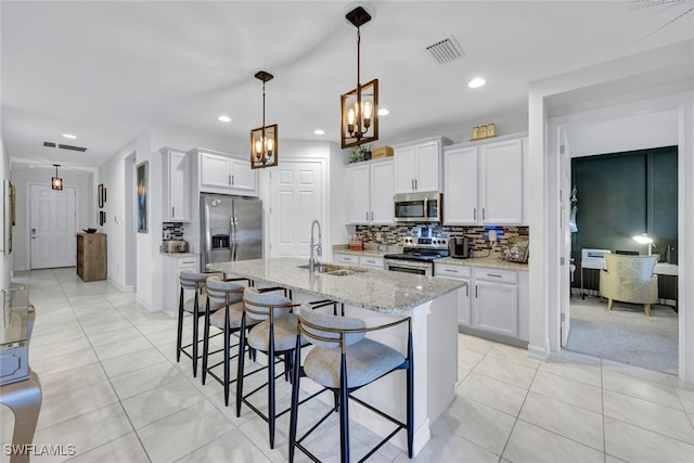 kitchen with stainless steel appliances, white cabinetry, an island with sink, and sink