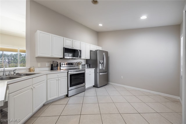 kitchen with white cabinets, light tile patterned flooring, sink, and stainless steel appliances