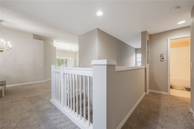 hallway with a notable chandelier and carpet floors