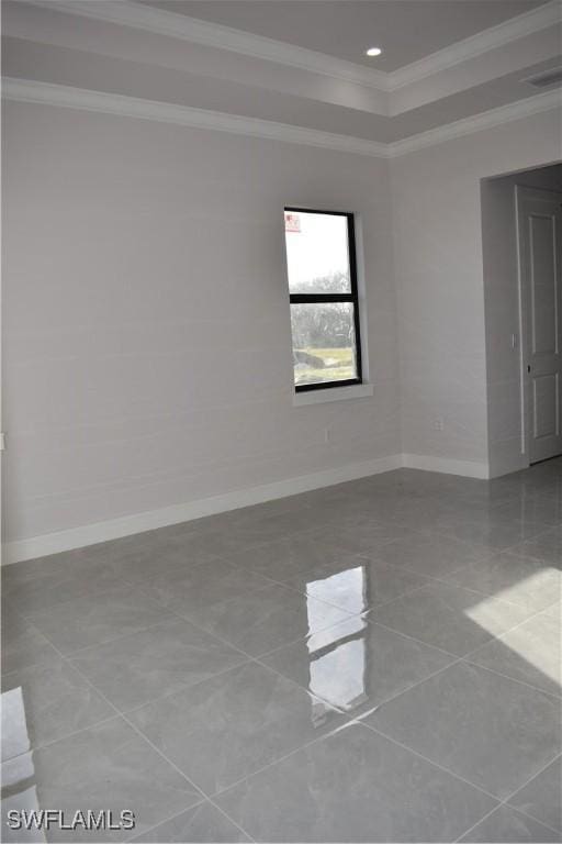 empty room featuring a raised ceiling and ornamental molding