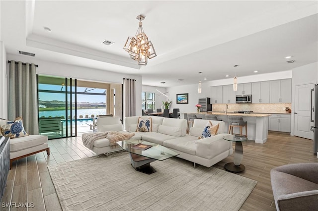 living room with a water view, sink, and a tray ceiling