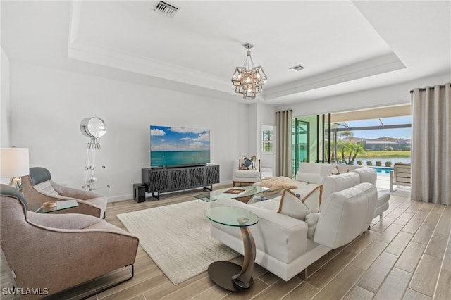 living room featuring a tray ceiling and an inviting chandelier