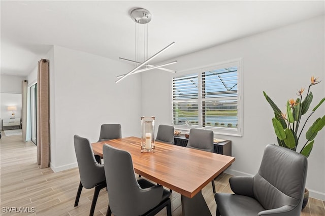 dining space with light hardwood / wood-style floors and a notable chandelier