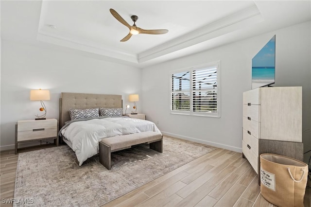 bedroom featuring a tray ceiling, ceiling fan, and light hardwood / wood-style floors