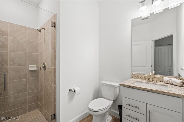 bathroom featuring vanity, toilet, wood-type flooring, and tiled shower