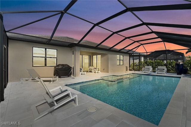 pool at dusk with a lanai, a jacuzzi, and a patio