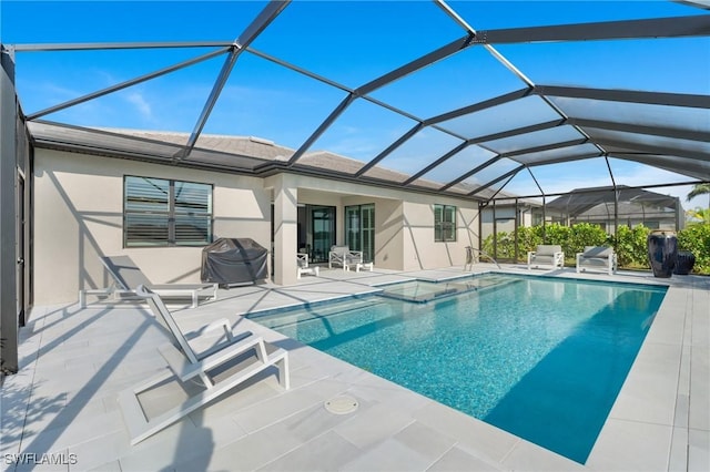 view of pool featuring glass enclosure, grilling area, and a patio area