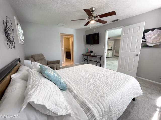 bedroom with connected bathroom, ceiling fan, light carpet, and a textured ceiling