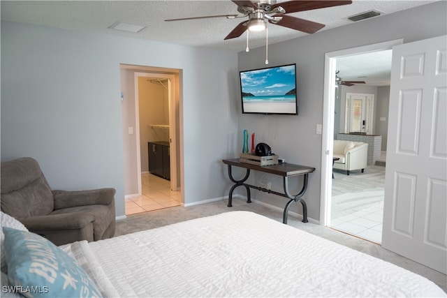 carpeted bedroom with a textured ceiling, ceiling fan, and ensuite bathroom