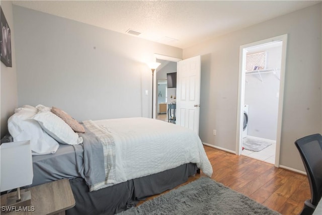 bedroom featuring wood-type flooring, a textured ceiling, a spacious closet, and a closet