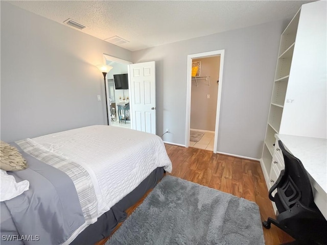 bedroom featuring dark hardwood / wood-style flooring, a walk in closet, a textured ceiling, and a closet