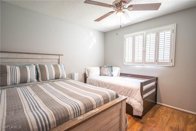 bedroom with hardwood / wood-style floors, ceiling fan, and a textured ceiling