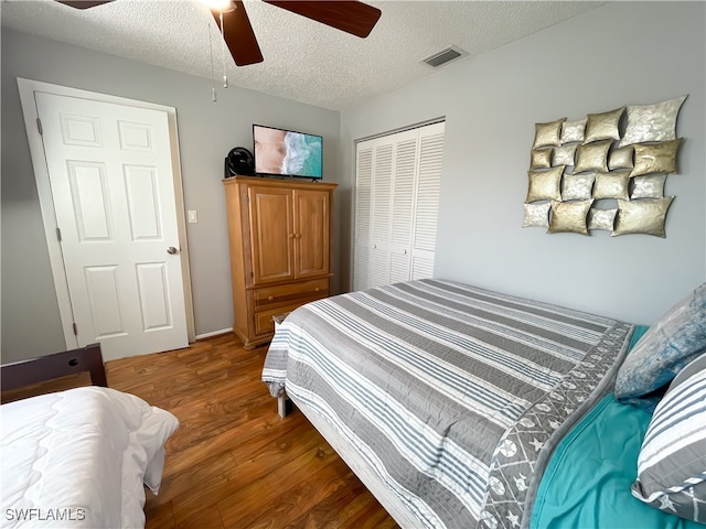 bedroom with ceiling fan, a closet, dark wood-type flooring, and a textured ceiling