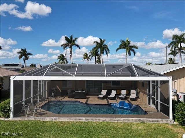 back of property featuring outdoor lounge area, glass enclosure, a yard, and a patio